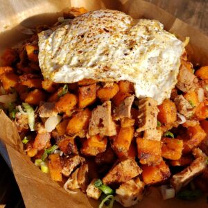 Sweet potato hash composed of a generous serving of cubed cooked sweet potatoes, topped with a fried egg.