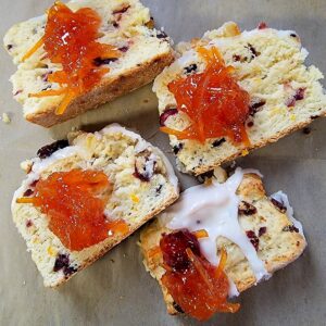 A tray of cranberry-orange scones cut in half and topped with house-made orange marmalade