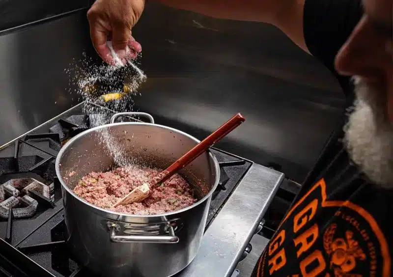 Adding salt & pepper to a pot on the stove.